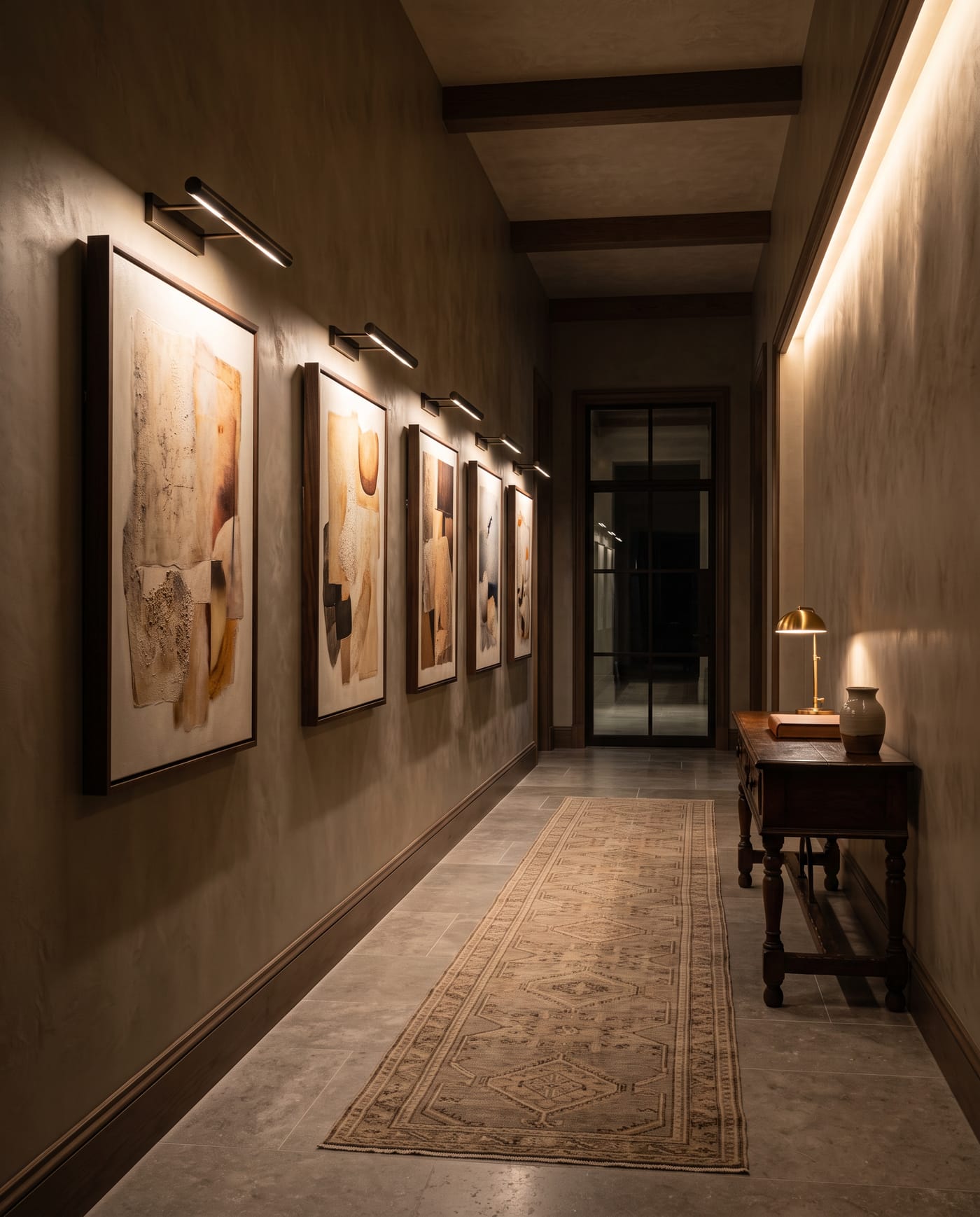 The gallery corridor in the evening, artworks each held in a pool of warm light